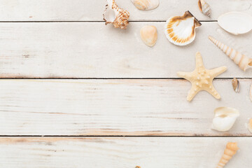 Sea shells, starfish and sand on wooden background, top view