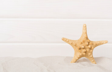 Fototapeta na wymiar Starfish on sand against wooden background