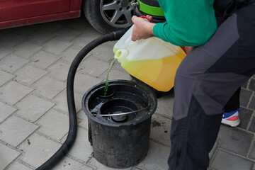 Pouring cleaning liquid into a bucket from a bottle for professional extraction vacuum cleaner