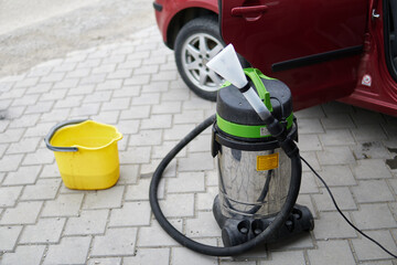 Professional extraction vacuum cleaner with car in background - obrazy, fototapety, plakaty