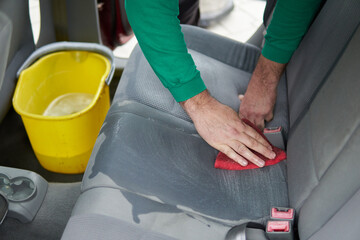 Car cleaning detailing - male using professional steam vacuum chemical cleaning for dirty car...