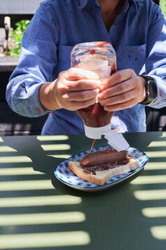 Person squirting ketchup on sanga sandwich