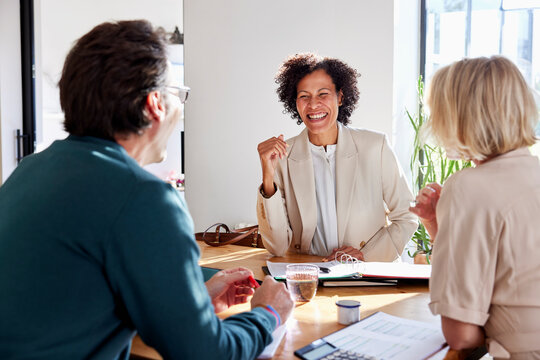 Smiling financial advisor discussing sales performance with couple 