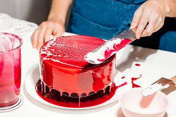 The pastry chef prepares a bright glazed mousse cake in a web effect