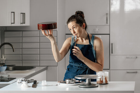 The pastry chef is intently trying an attractive mousse cake