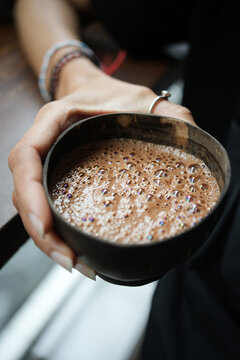 Cocoa ceremony details, hands holding hot drink in coconut shell