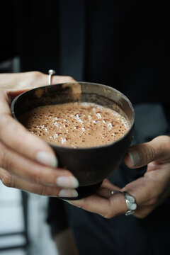 Cocoa ceremony details, hands holding hot drink in coconut shell