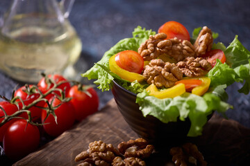 Fresh ripe vegetables on a beautiful table with walnuts. Vegetarian healthy breakfast, snack or lunch consisting of a salad of fresh vegetables and walnuts, seasoned with vegetable oil. 