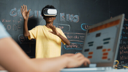 Closeup of school girl hand coding program while african student using VR interact with metaworld....