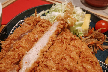 Plate of traditional Japanese tonkatsu, featuring a crispy, golden-brown breaded pork cutlet...