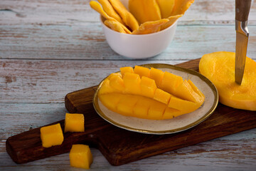  Close-up on a plate of sliced juicy pulp of tropical sweet mango. Healthy fruit snack of ripe mango and slices of sweet candied fruit.