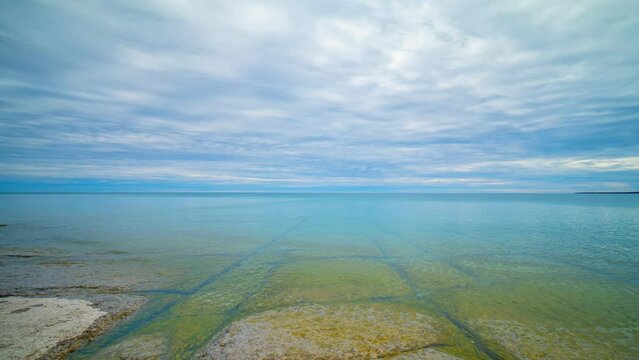 Timelapse of Prince Edward County Beach in Ontario. Lake Ontario in Canada. Prince Edward County, Point Petre Beach irregular headland or littoral made of limestone cliffs. Calm water time lapse.