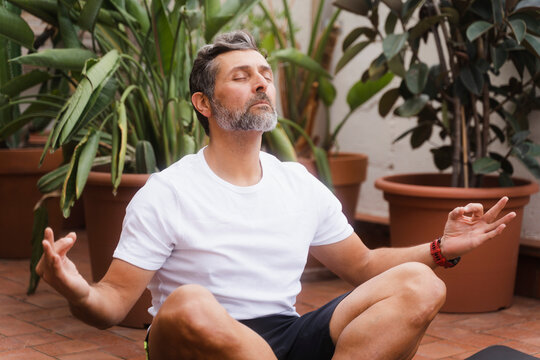 Senior Man Meditating On Terrace At Home