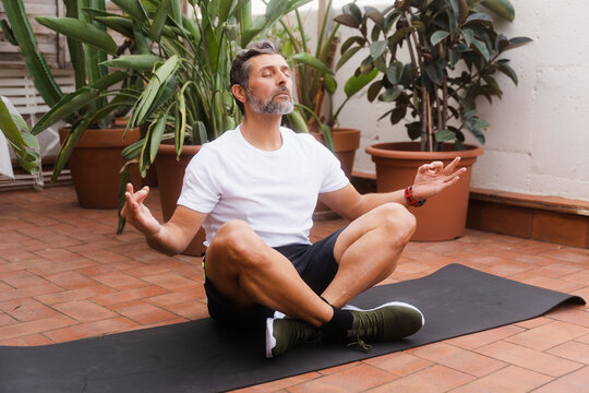 Senior Man Meditating On Terrace At Home