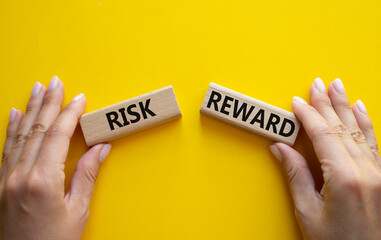 Risk or Reward symbol. Concept word Risk or Reward on wooden blocks. Businessman hand. Beautiful yellow background. Business and Risk or Reward concept. Copy space