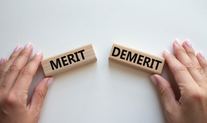 Merit or Demerit symbol. Concept word Merit or Demerit on wooden blocks. Businessman hand....