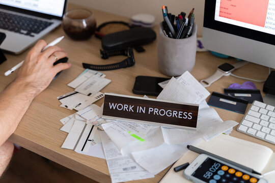 man works online at messy workplace with receipts, invoices