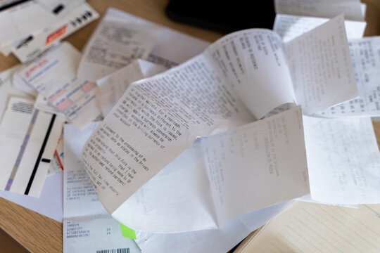 Messy workplace desk with utility bills, tax forms, invoices, receipts