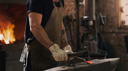 Blacksmith, man and hands with metal, hammer and flame with equipment for professional craft....