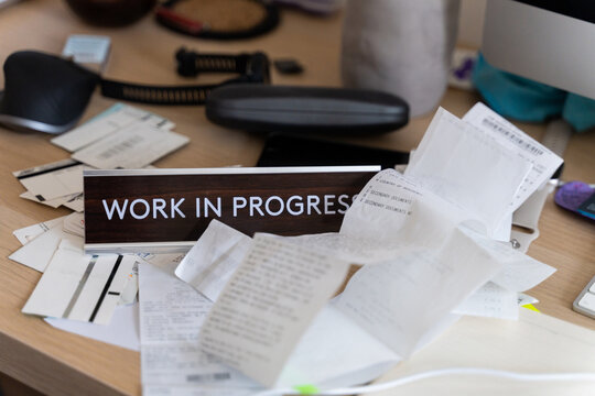 Messy workplace desk with utility bills, tax forms, invoices, receipts