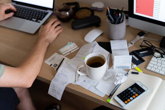 Man works in messy workplace with tea cup on receipts, invoices