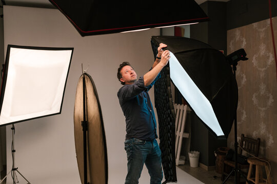 Focused man putting grid on softbox in studio