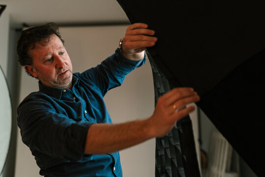 Adult man adjusting flashlight in photo studio