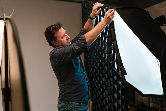 Adult man photographer putting grid on softbox