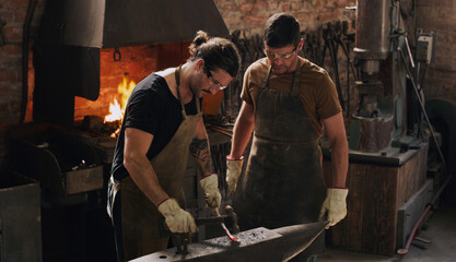 Blacksmith, colleagues and hammer with metal, flame and equipment for professional craft....