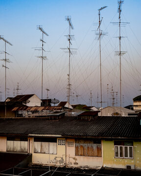 Lots of antenna and electrical wires on rooftops at sunset in Thailand