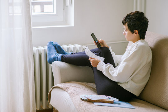 Young woman pays heating bill with smartphone