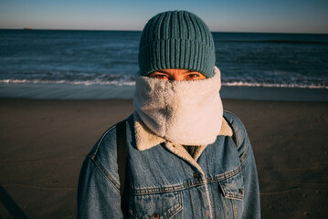 Close-Up Portrait of a young woman in Winter outfit at the ocean