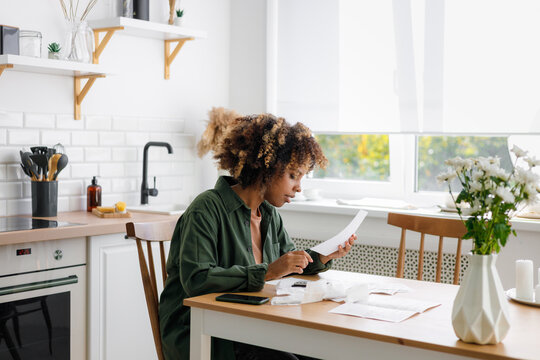 Serious curly haired female manages household family budget.