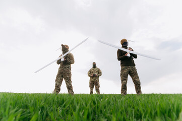 soldiers are standing in the field holding drones. The concept of using drones in smart warfare.