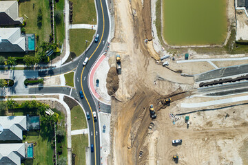 Industrial construction roadworks at roundabout intersection with moving cars in Venice, Florida. Development of urban circular transportation crossroads