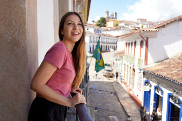 Young woman looking out from the balcony in the historic city of Ouro Preto, UNESCO World heritage...