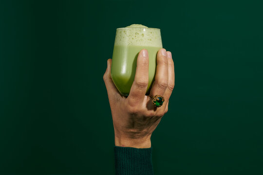 man holds a glass with iced matcha latte