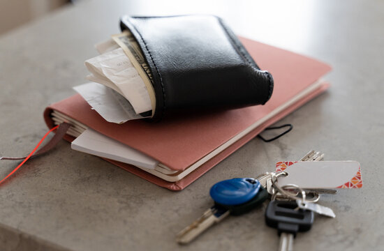 messy wallet with receipts and cash US dollars, notebook and keys