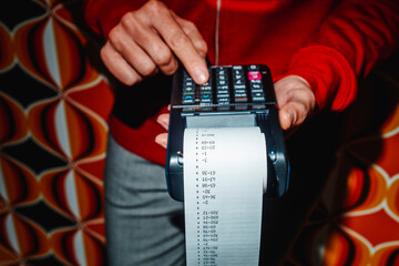 man using an electronic calculator with a paper-roll