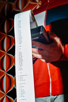 man holding a calculator with a long strip of calculations