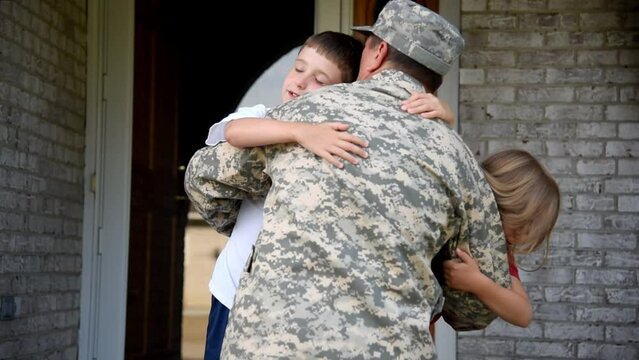 A soldier man is coming home in the door and hugging his children for a love, family or reunited concept.