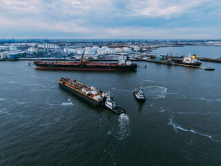 Tugboats Guiding a Freighter in Harbor, drone view