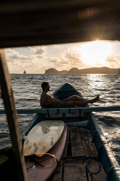 Surfer Reclining on Boat, Summer Vives Golden Hour in Indonesia