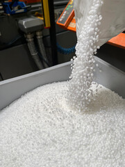 pouring of a bag of white plastic pellets on a gray plastic drawer, production of plastic parts,...