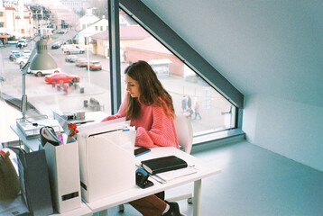 Young woman in pink sweater working at the table in office