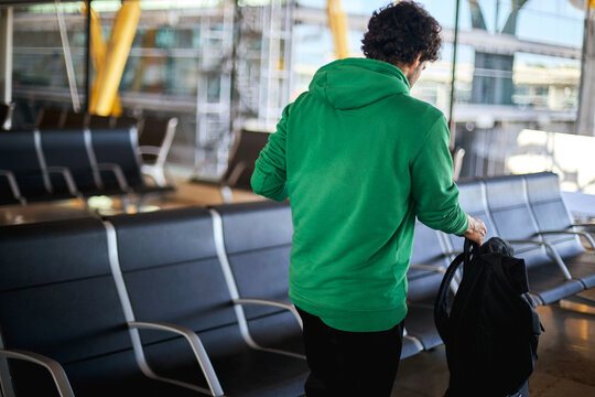 A young man walking and finding a seat at the airport terminal.