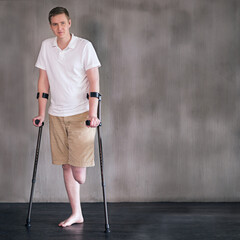 Portrait, crutches and man with disability in healthcare centre for walking, muscle strength and...