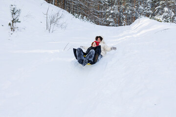Girls sliding down a slope in the winter woods 
