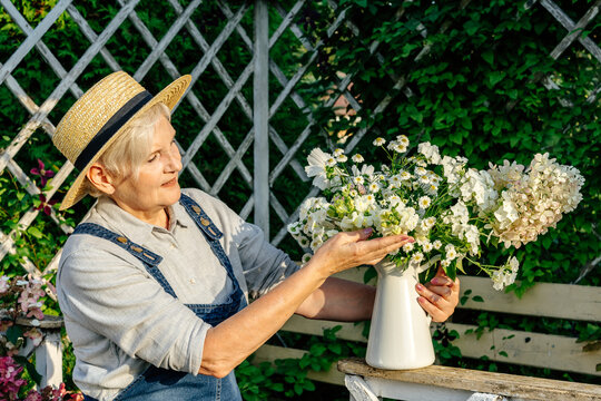Senior woman arranging flower bouquet in vase