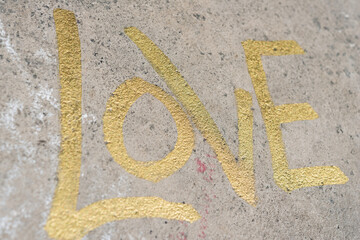 love in gold metallic ink marker on concrete